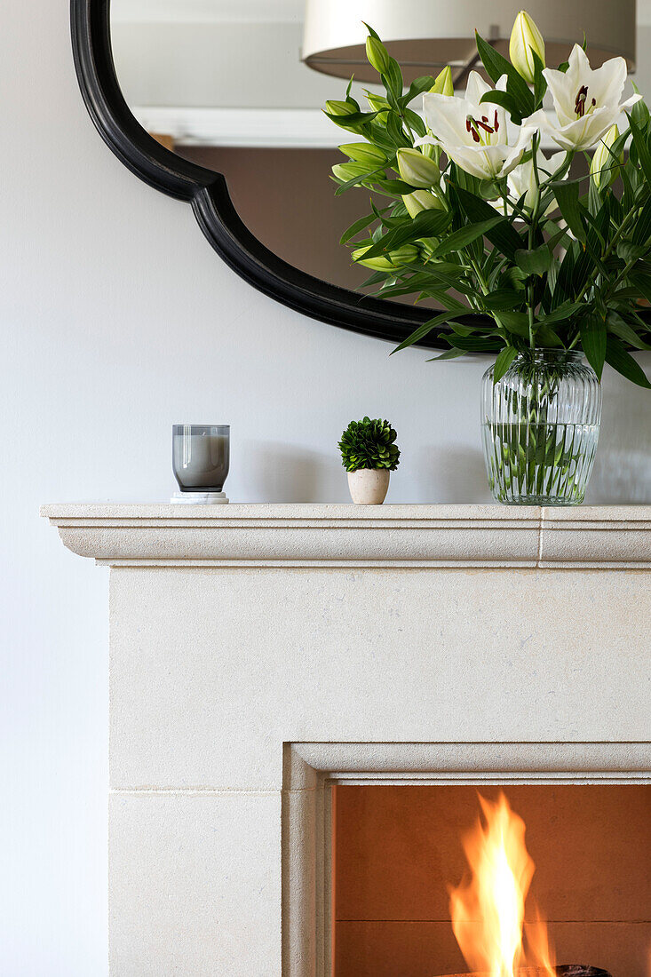 Lilies on mantlepiece above lit fire in Surrey home UK