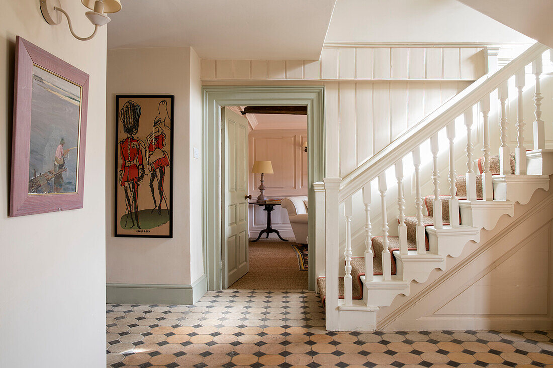 Weißes Treppengeländer mit kariertem Fliesenboden in einem Haus in Somerset, England