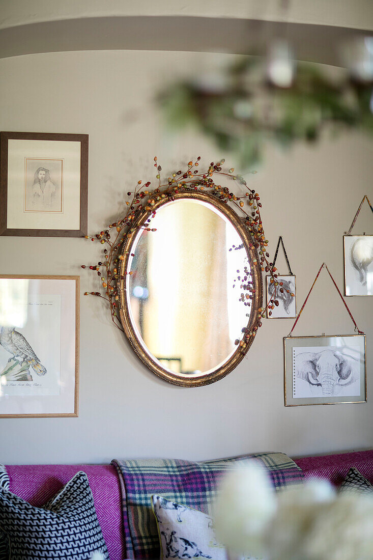 Ovaler Spiegel mit Beeren und gerahmten Kunstwerken in einem Haus in Somerset, UK