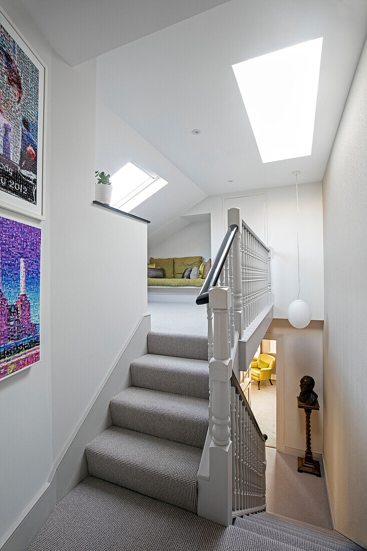 Grey carpeted staircase below skylight with modern art in London home UK
