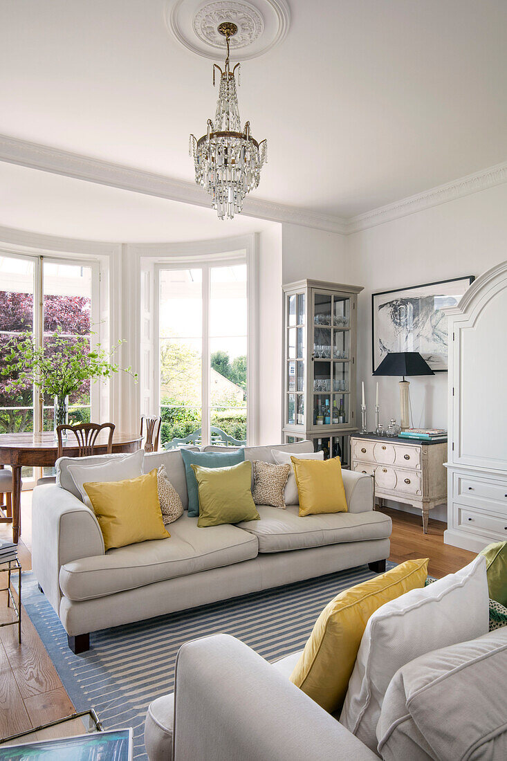 Yellow cushions on sofa below glass chandelier in Grade II listed villa Arundel West Sussex UK