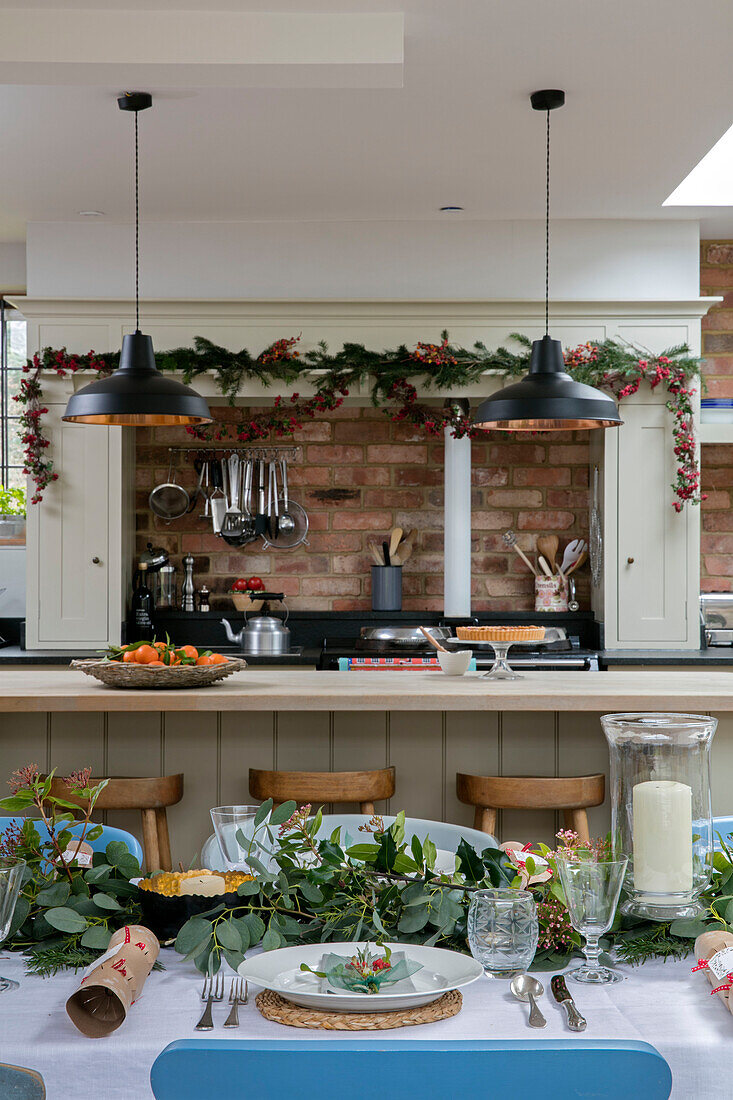 Schwarze Pendelleuchten über der Frühstücksbar mit einem für das Weihnachtsessen gedeckten Tisch in einem Haus im Stil der 1930er Jahre in West Sussex, Großbritannien