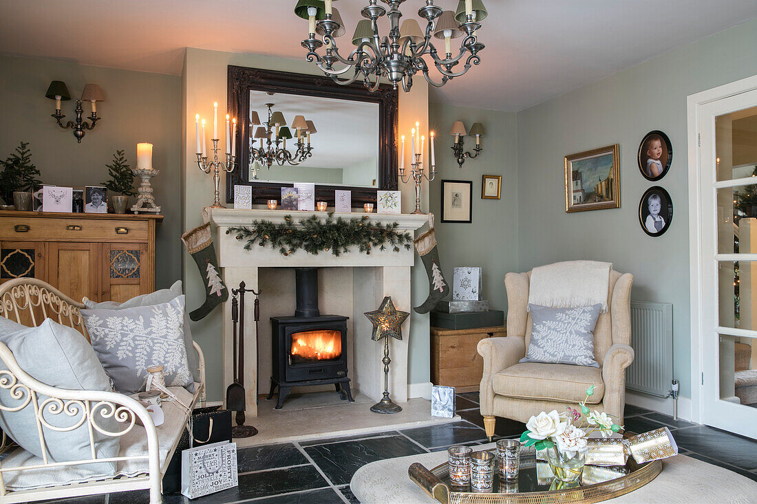 Armchair and sofa at fireside with lit woodburner in Hampshire home