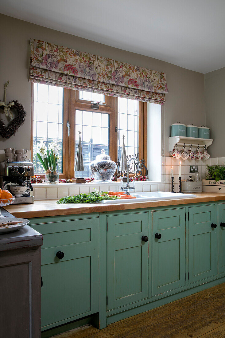 Grüne Küchenschränke unter Bleiglasfenster mit Raffrollo in einem Haus in Hampshire