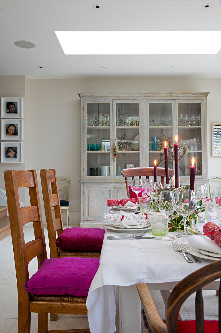 Pinkfarbene Sitzkissen auf Stühlen am Esstisch mit brennenden Kerzen im Anbau eines edwardianischen Hauses in East Dulwich London UK