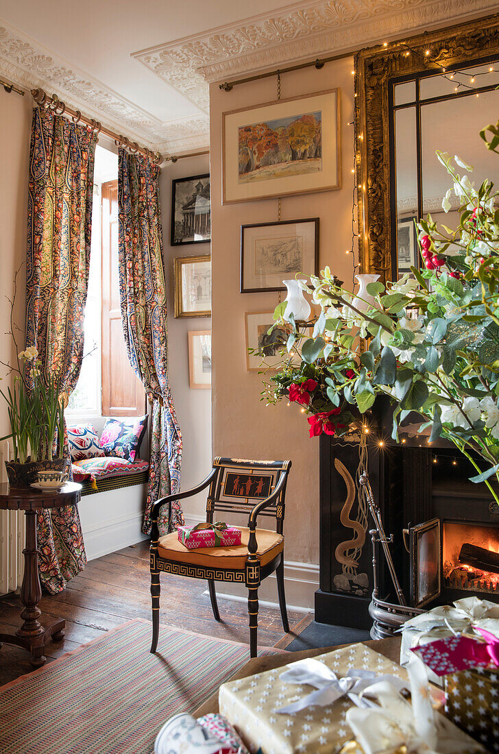 Antique chair at black stone fireside with floral curtains and windowseat n Georgian hallway Hertfordshire England UK