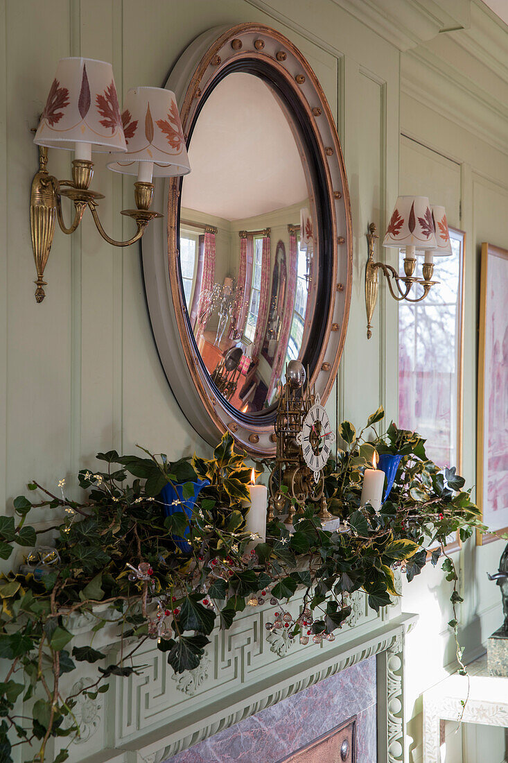 Christmas garland on mantlepiece below convex mirror in Georgian home Hertfordshire England UK