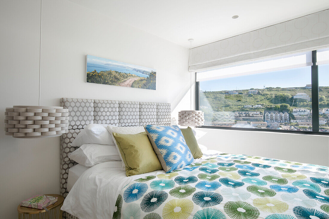 Blue and green duvet on bed at window with view of Cornwall UK