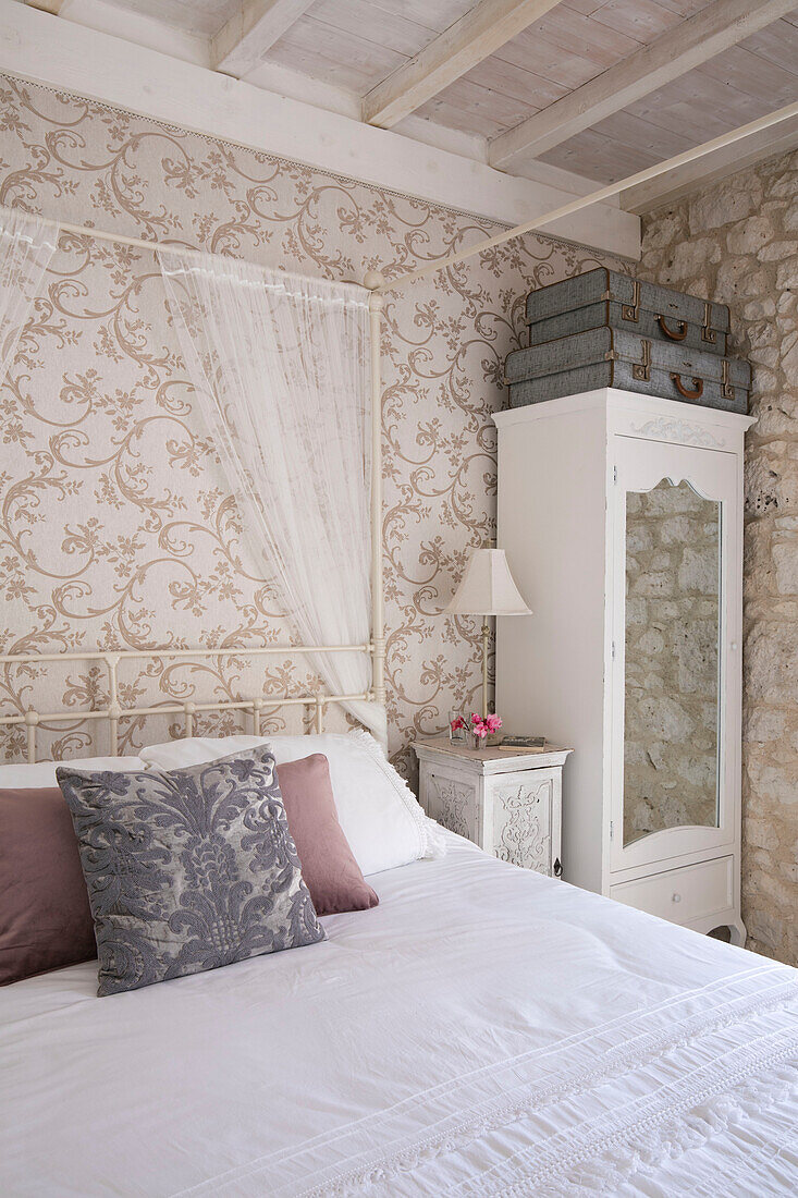 Vintage suitcases on wardrobe in bedroom with cream an gold wallpaper in 13th century Dordogne home France