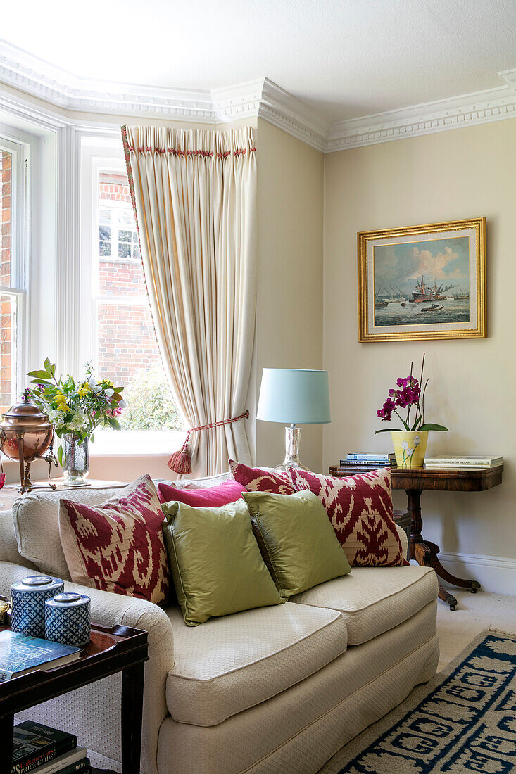 Verschiedene Kissen auf Zweisitzer-Sofa im Erkerfenster eines Wohnzimmers in Hampshire UK