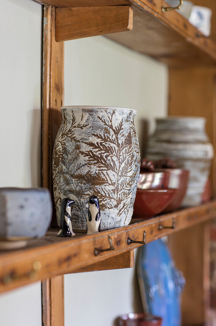 Keramikvase mit Keramikpinguinen auf einem Holzregal in der Küche eines Landhauses in Northamptonshire aus dem 17