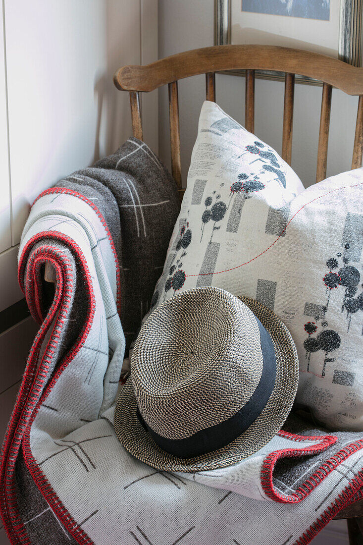 Sunhat and blanket with floral cushion on wooden chair in North London home UK
