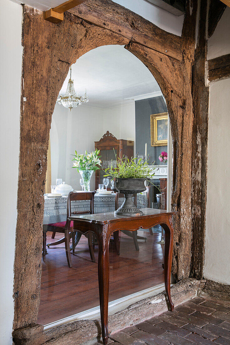 Holztisch mit zwei L-förmigen Beinen in einem originalen gewölbten Balken eines Landhauses in Kent UK