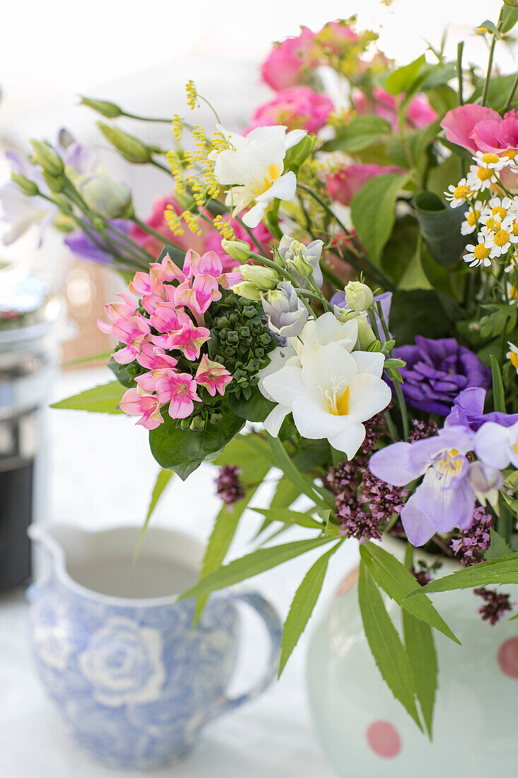 Sommerblumen und Milchkännchen auf einem Tisch in einem Haus in Sussex, Großbritannien