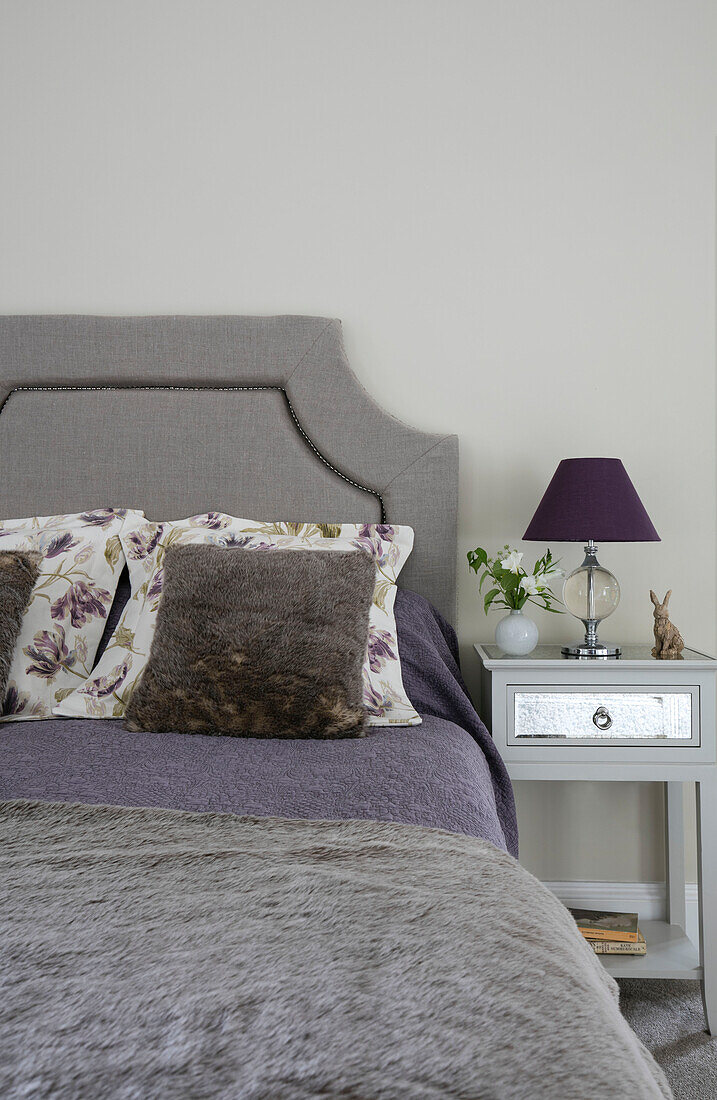 Graues Kopfteil und Decke mit violetter Lampe am Bett in einem Haus in Sussex, UK