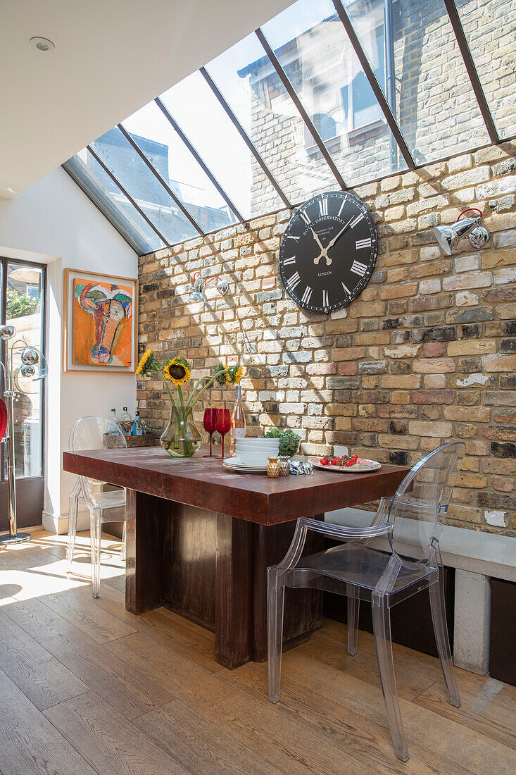 Clock above table with exposed brick wall and skylight in Edwardian terrace conversion London UK