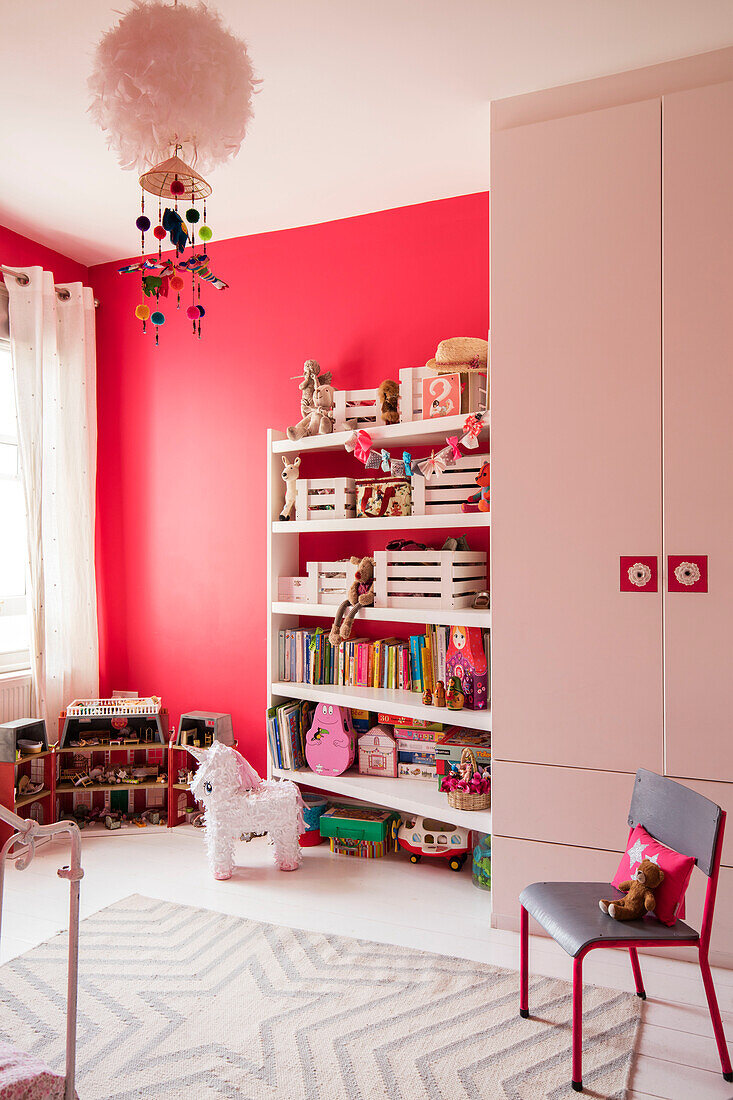 Kleiderschrank und Stuhl mit Spielzeug und Büchern auf Regalen im Spielzimmer eines Londoner Hauses UK