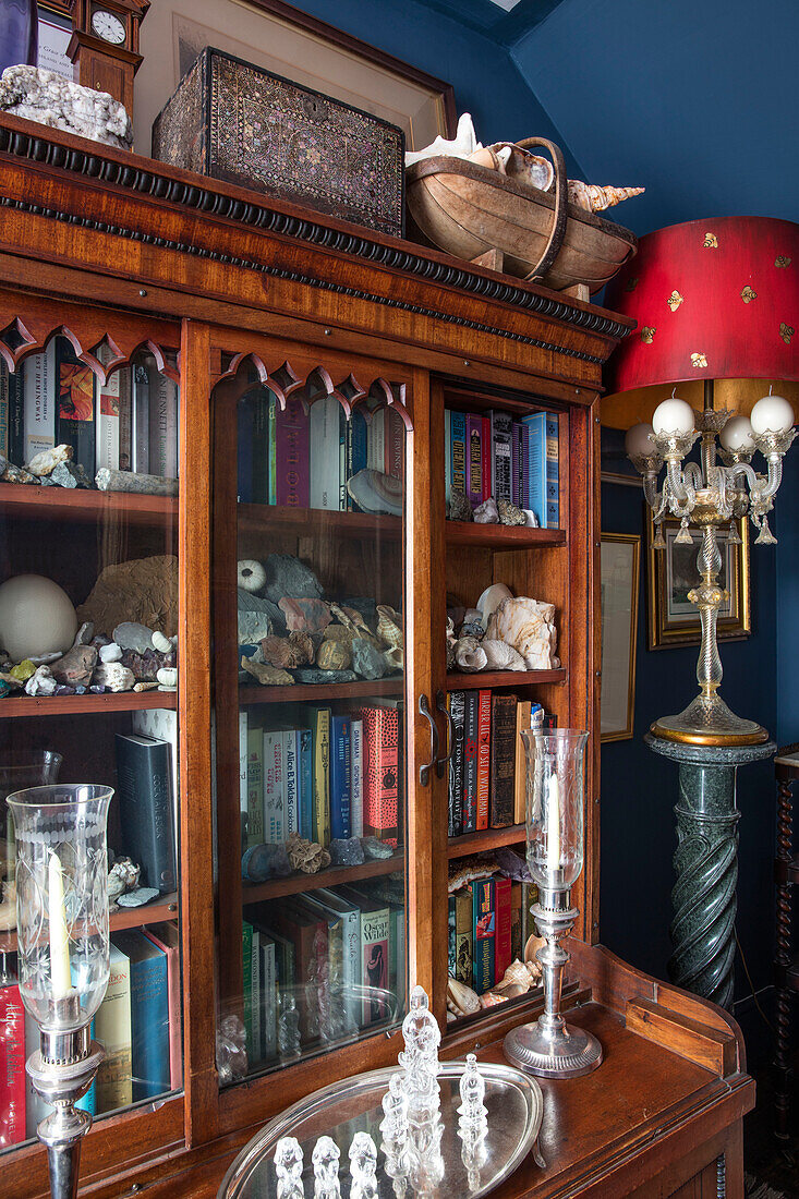 Antike Laternen mit einer Sammlung von Kieselsteinen und Büchern in einer Vitrine in einem Haus in Sussex