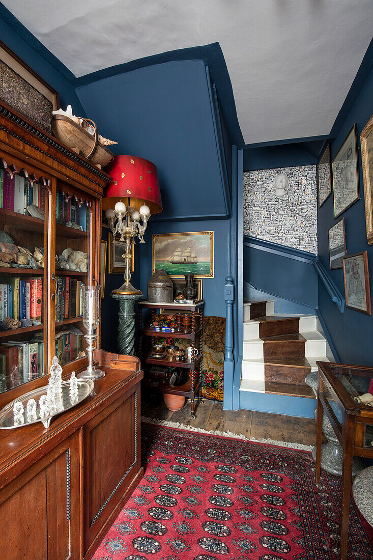 Antique bookcase and rug in blue hallway of Sussex home