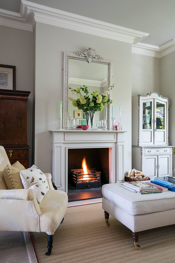 Armchair and ottoman with lit fire in London living room UK