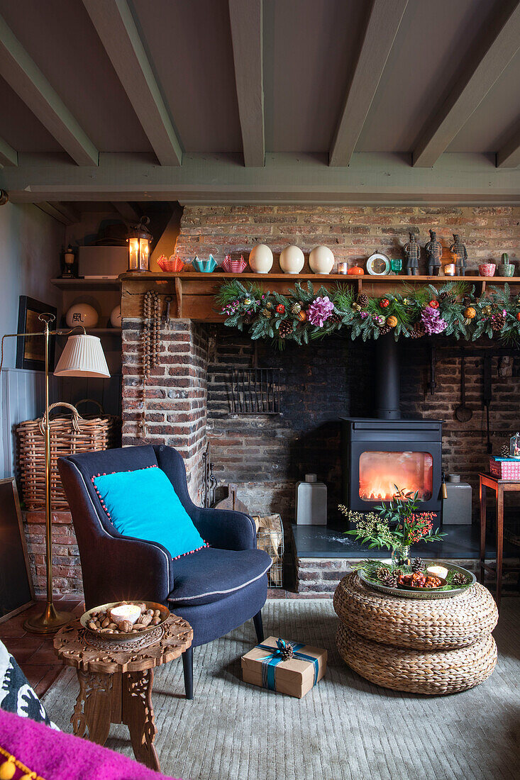 Armchair at fireside with wicker footstool in Norfolk cottage England UK