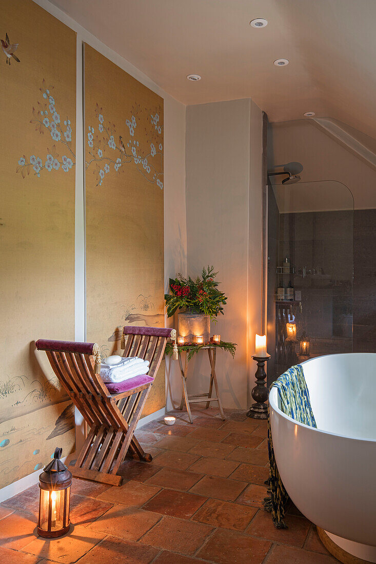 Freistehende Badewanne und hölzerner Fußhocker mit orientalischer Wandverkleidung und wiederverwendeten Terrakottafliesen in einem Landhaus in Norfolk, England UK