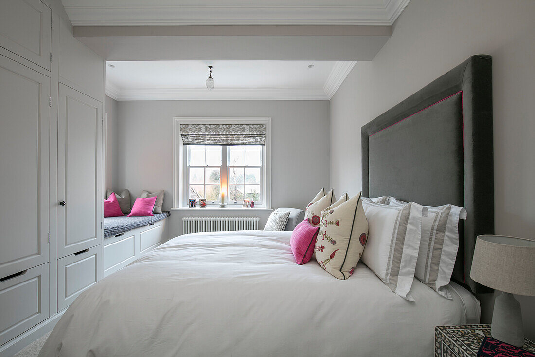 Großes graues Kopfteil über dem Bett in einem Zimmer mit Einbauschrank und Fensterplatz Hampshire UK