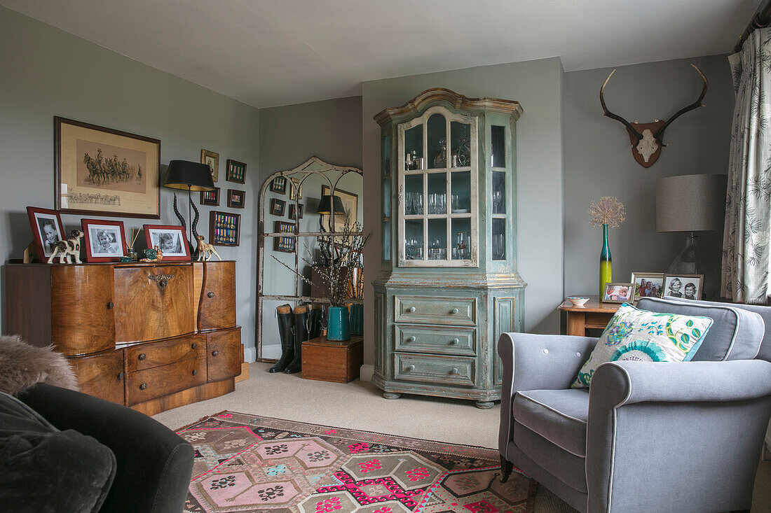 Grauer Sessel und Vintage-Schrank und Anrichte im Wohnzimmer in Hampshire England UK