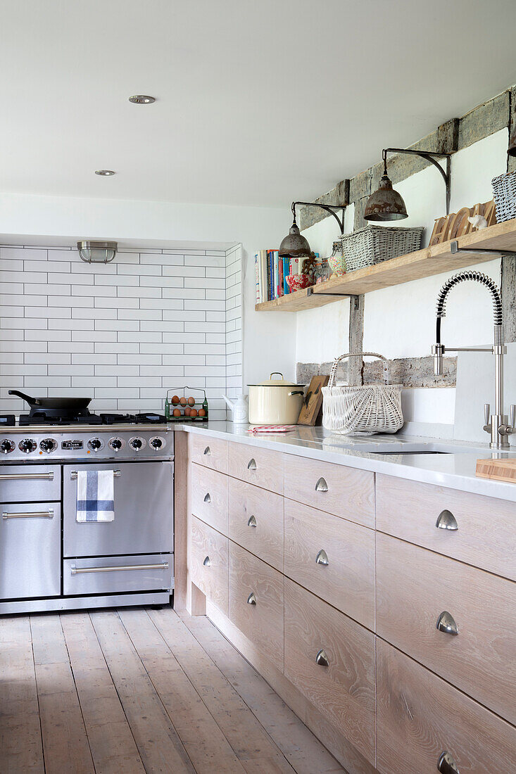Regal aus Gerüstbrettern über Schubladen aus gekalkter Eiche mit Edelstahlherd in einer Küche in Surrey UK