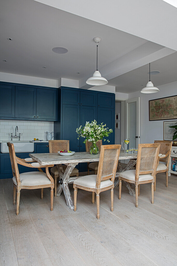 Pendelleuchten über einem Tisch aus wiederverwendeten Gerüstplänen mit blauem Anstrich in der Küche einer Wohnung im Norden Londons UK