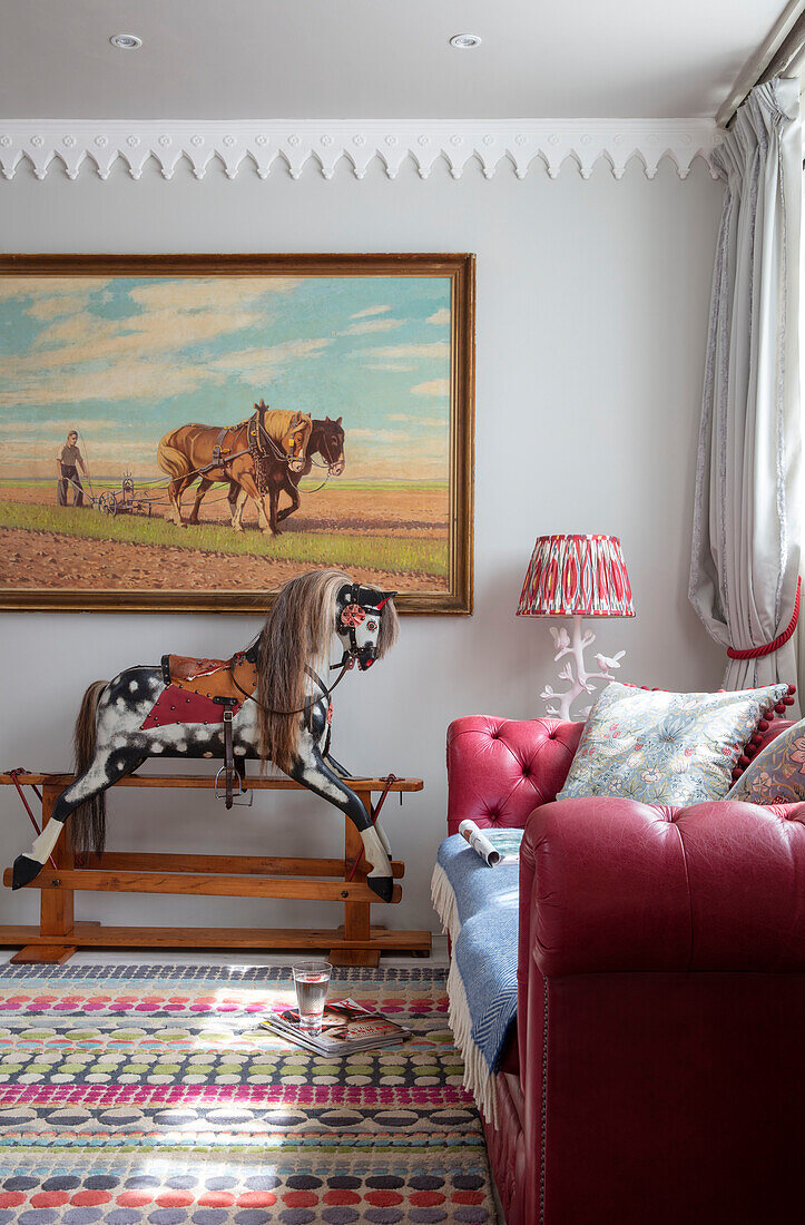 red leather sofa and rocking horse in 1840s Cotswolds cottage Oxfordshire UK