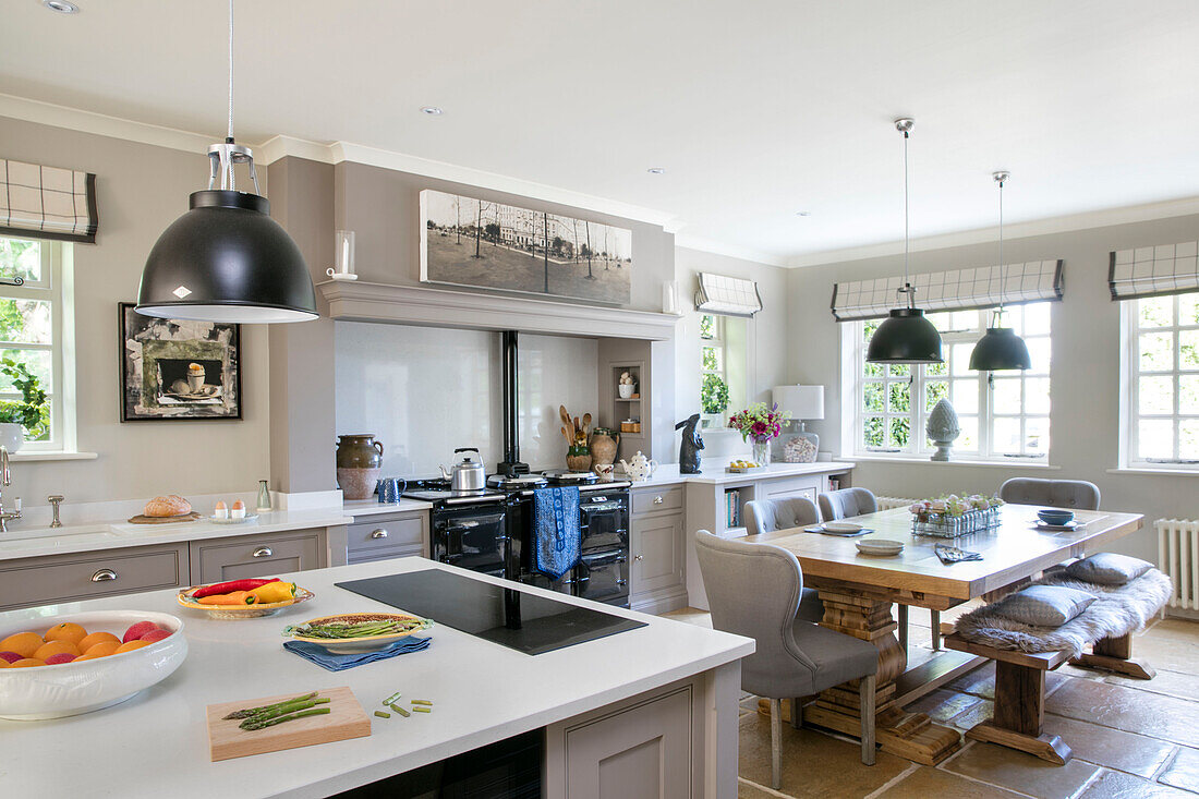Open plan kitchen with table and black pendant shades in former Victorian coach house West Sussex UK