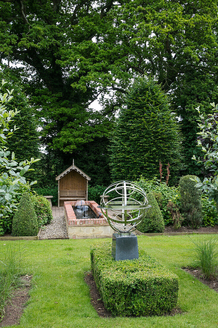 Armillarsphäre und Wasserspiel im begrünten Garten des Hauses in West Sussex, England, UK