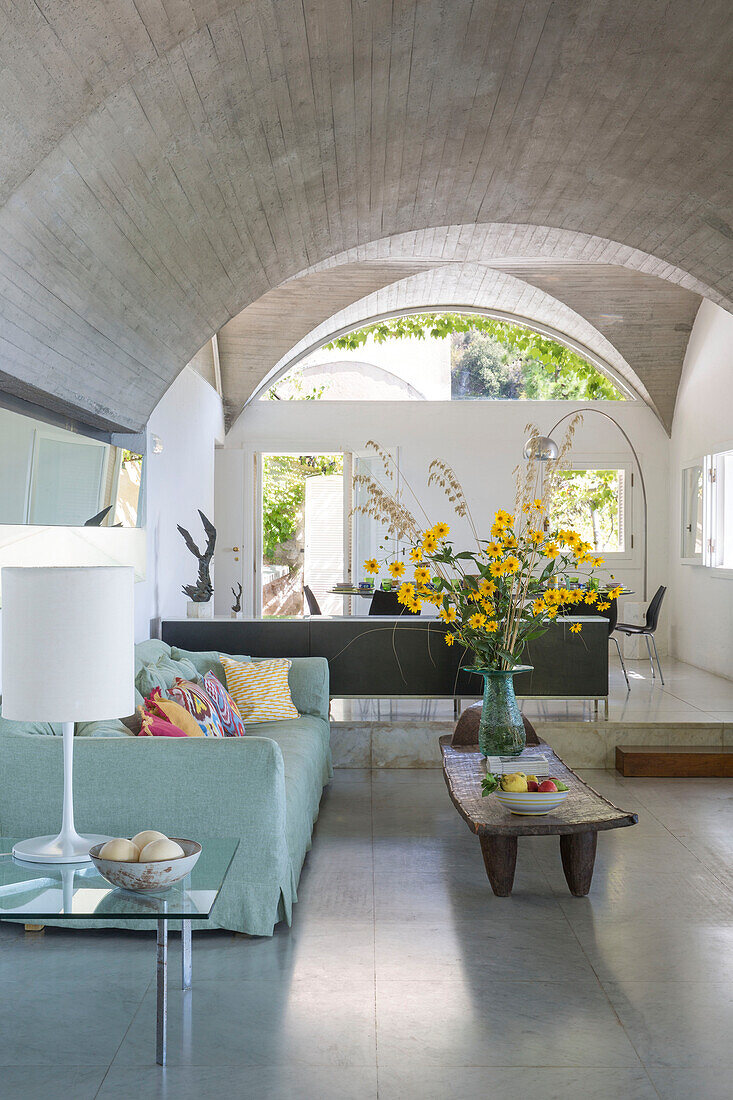 Blumen auf Couchtisch mit hellgrünem Sofa in gewölbter italienischer Villa an der Amalfiküste