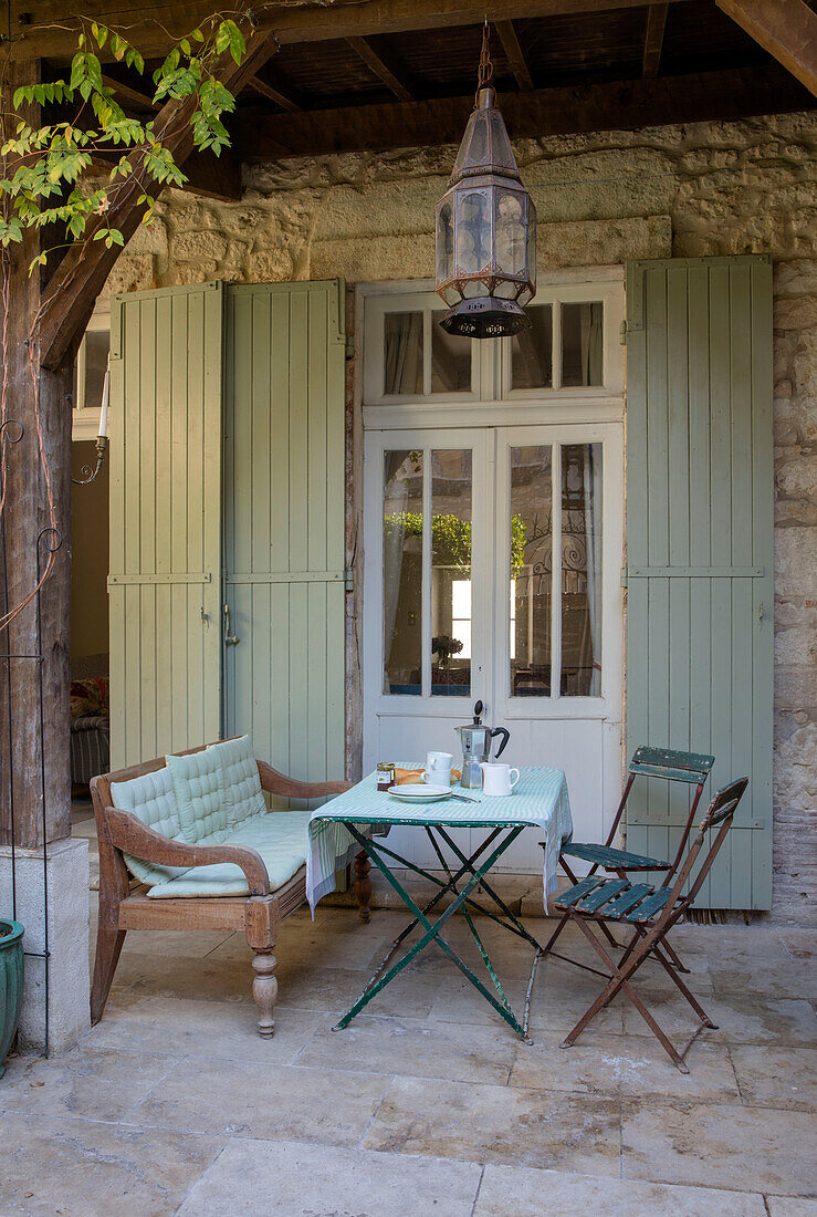 Hellgrüne Fensterläden mit Tisch und Stühlen im Innenhof eines Stadthauses in Issigeac im Perigord Frankreich