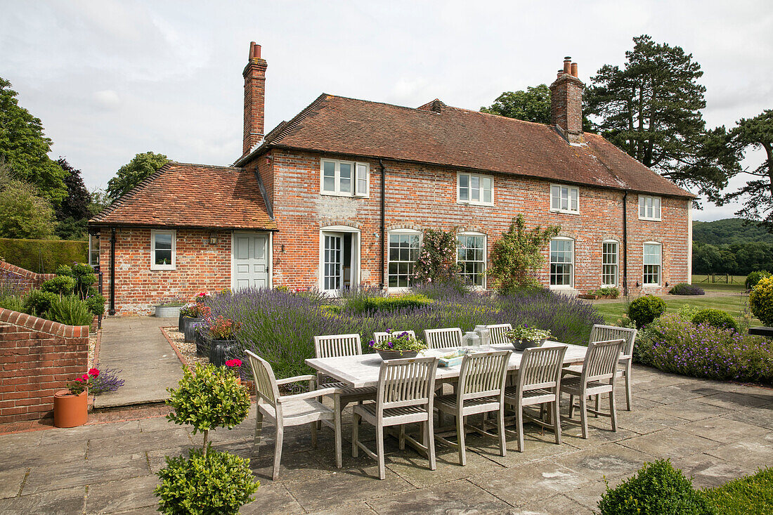Tisch und Stühle auf der Terrasse mit Lavendel im Garten eines Einfamilienhauses in Hampshire England UK