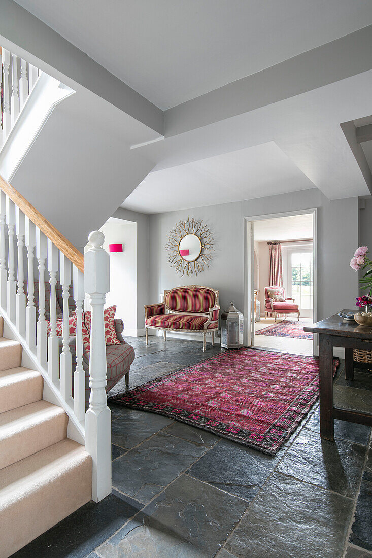 Patterned rug and two seater sofa in flagstone entrance hall of Hampshire home England UK