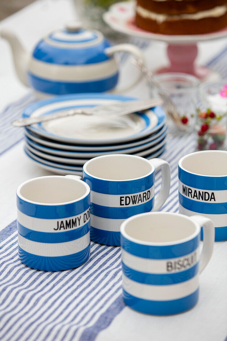 Blau-weiß gestreifte Tassen und Tischtuch im Garten in West Sussex UK