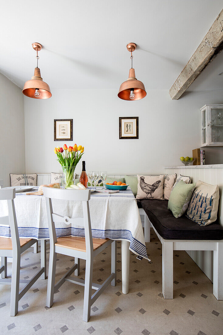 Tulpen auf einem Tisch mit Hühnerkissen und einer Bank mit Kupferanhängern in einem Landhaus in Wiltshire, UK