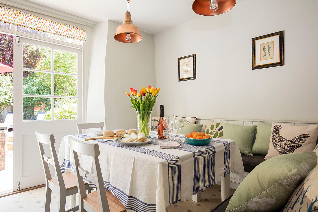 Tulips on table with hen cushions and copper pendants in Wiltshire cottage UK