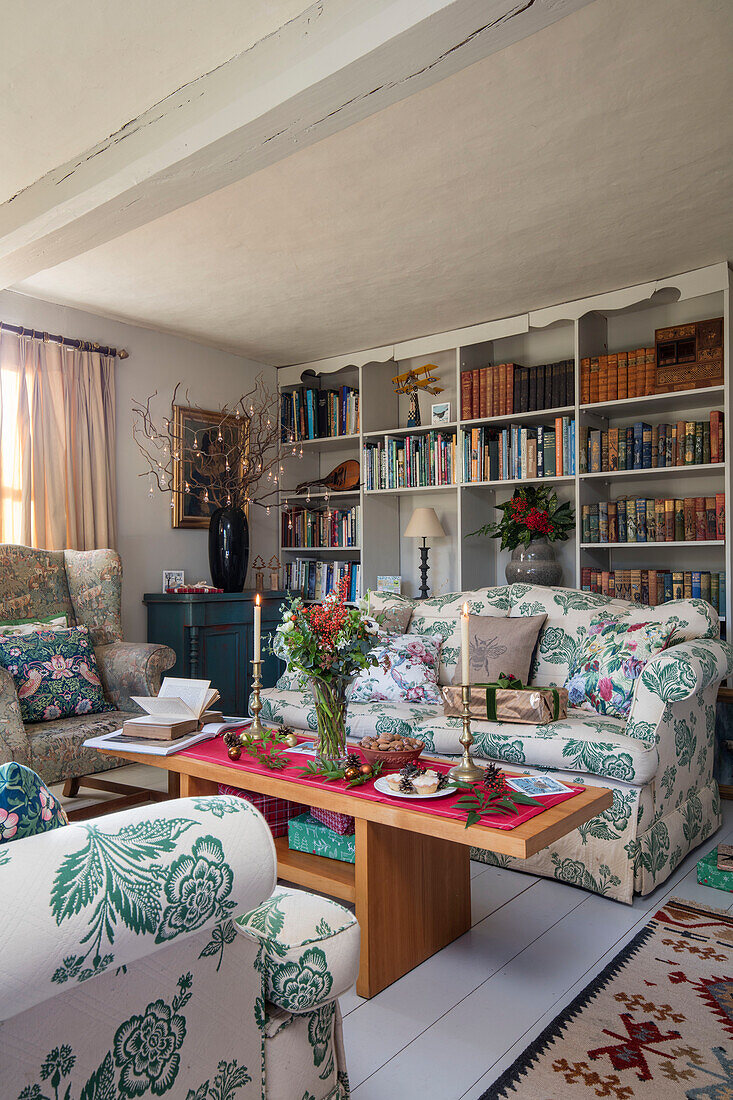Floral sofas and wooden coffee table with bookshelves in Norfolk farmhouse UK