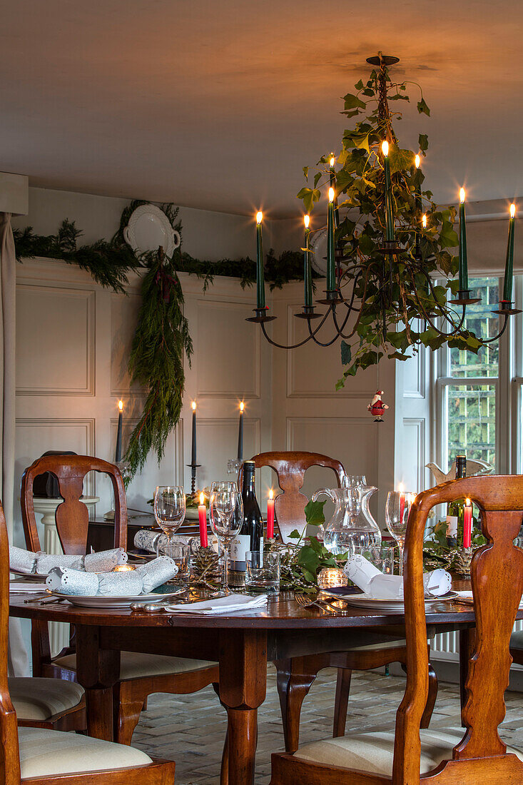 Esstisch und Stühle aus Holz mit weihnachtlichem Laub und Verkleidung in Paris Grey in der ehemaligen Molkerei eines Bauernhauses in Norfolk, UK