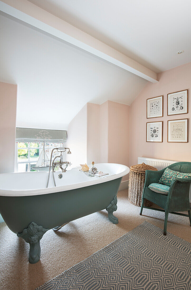 Clawfoot bath and wicker chair in window with walls in Pink Ground Grade II listed farmhouse Bodmin Cornwall UK