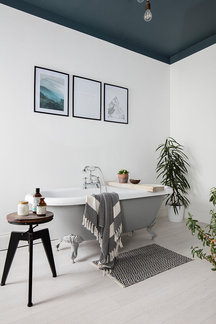 Framed prints above freestanding bath with ceiling painted Inchyra Blue in Cumbrian terrace UK