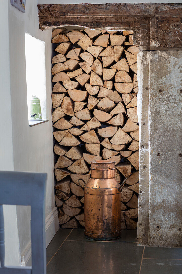 Brennholzlager mit antiker Milchkanne in einem unter Denkmalschutz stehenden georgianischen Bauernhaus (Grade II) Somerset, UK