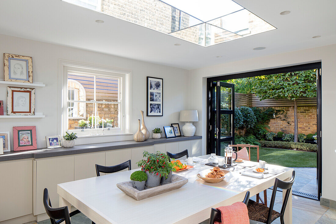Modern dining area with doors open to garden London UK