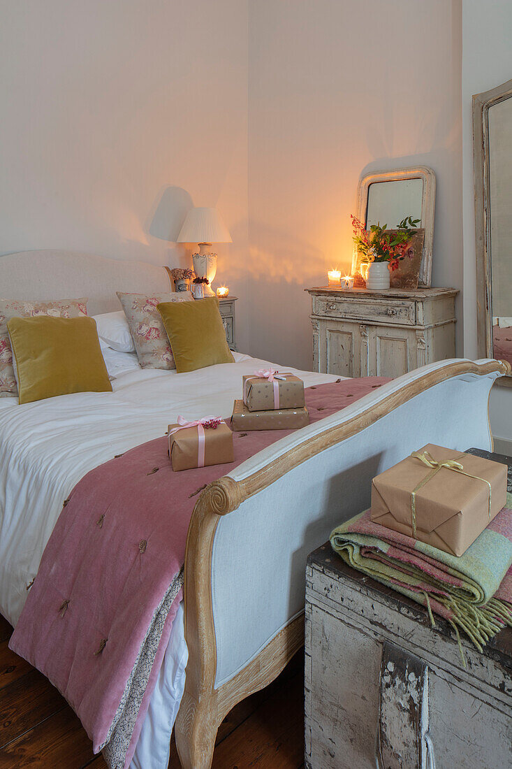 Bettgestell aus verwitterter Eiche mit Überwurf in Dusky Pink und gelben Samtkissen in einem Schlafzimmer in Hampshire UK
