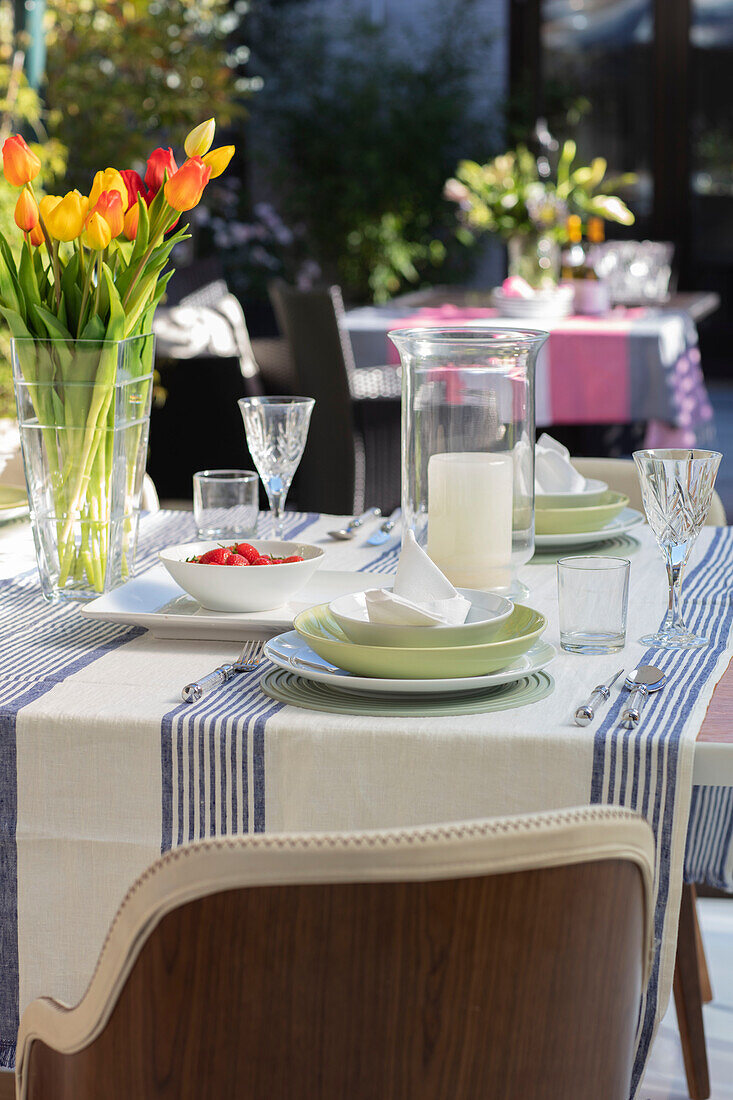 Tulpenvase auf gestreifter Tischdecke mit Platzdeckchen und Holzstuhl in einem Londoner Haus UK