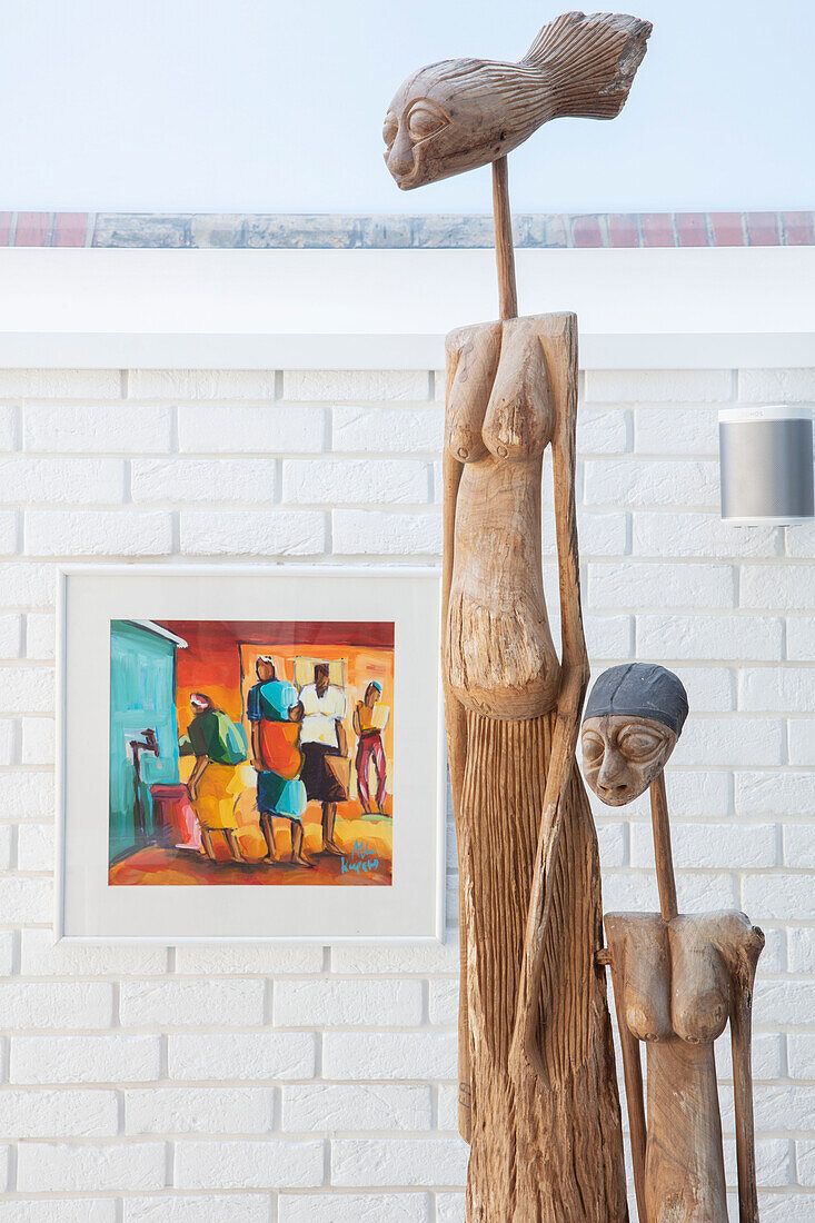 Zwei ethnische Skulpturen mit modernen Kunstwerken an einer weiß getünchten Wand in einem Londoner Haus, Großbritannien