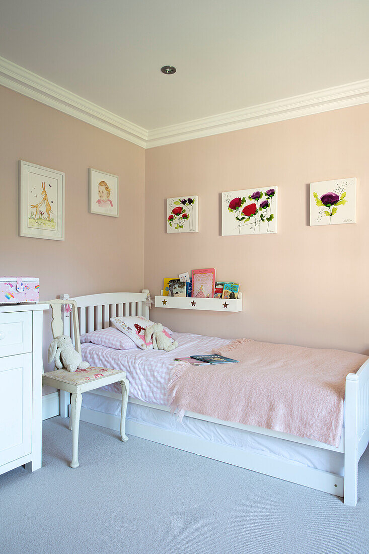 Kunstwerk an der Wand in Middleton Pink mit Kuscheltieren auf dem Bett in einem Mädchenzimmer in Hampshire UK